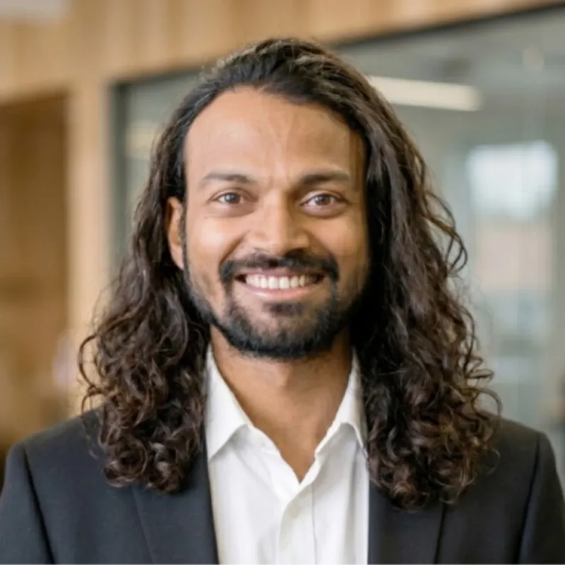 Naresh Kumar, smiling, in a dark blazer and white shirt